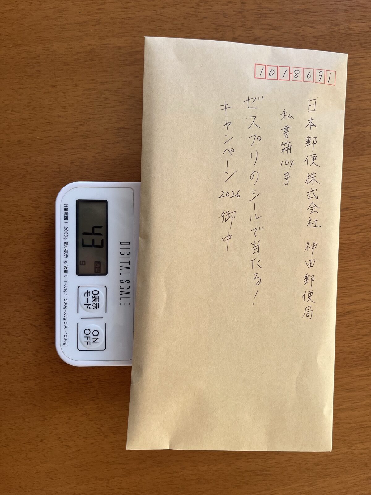 応募ハガキを入れた封筒をデジタルスケールで量り、43gと表示されているところ